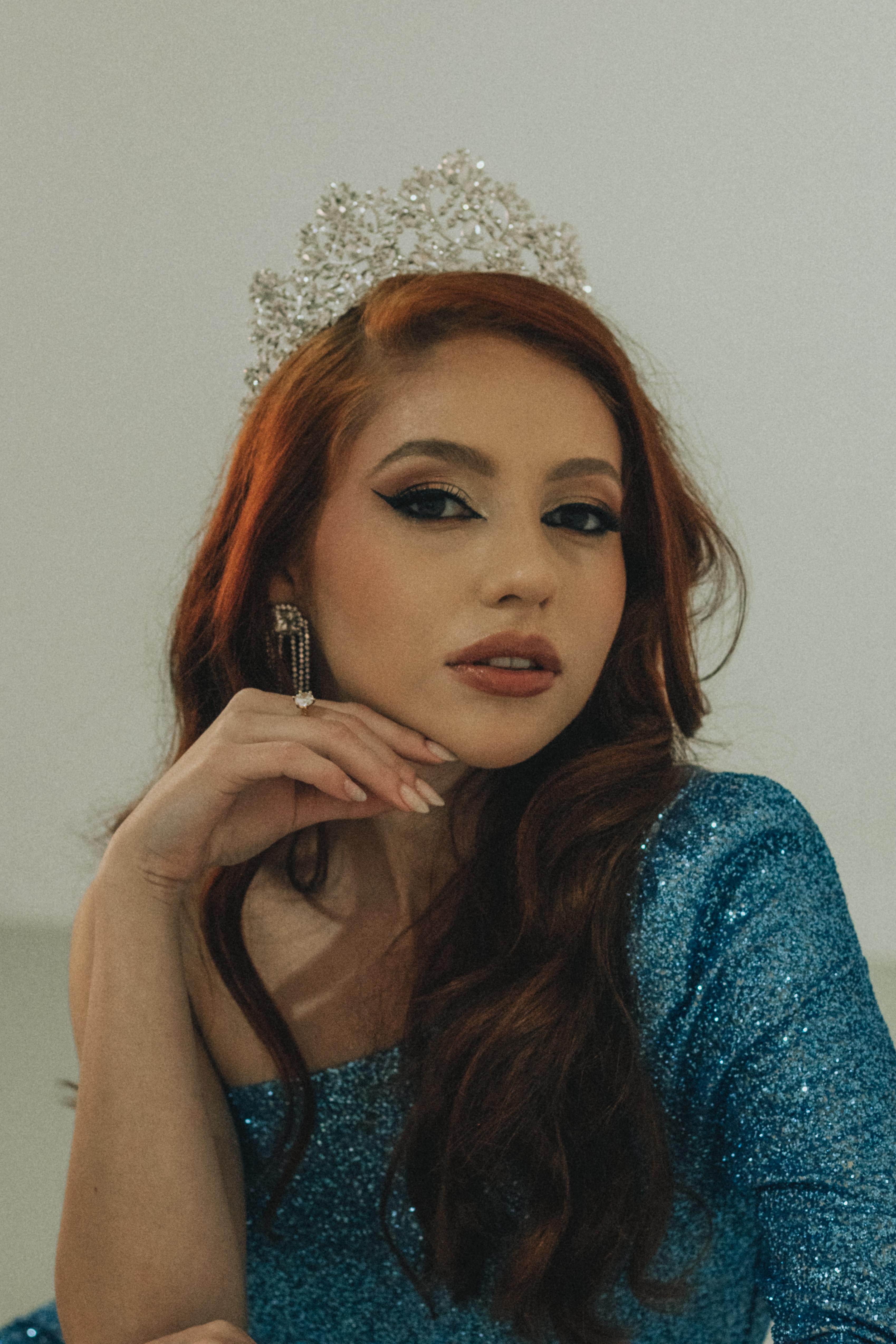 Stylish portrait of a woman wearing a tiara and glittery blue dress, exuding grace.