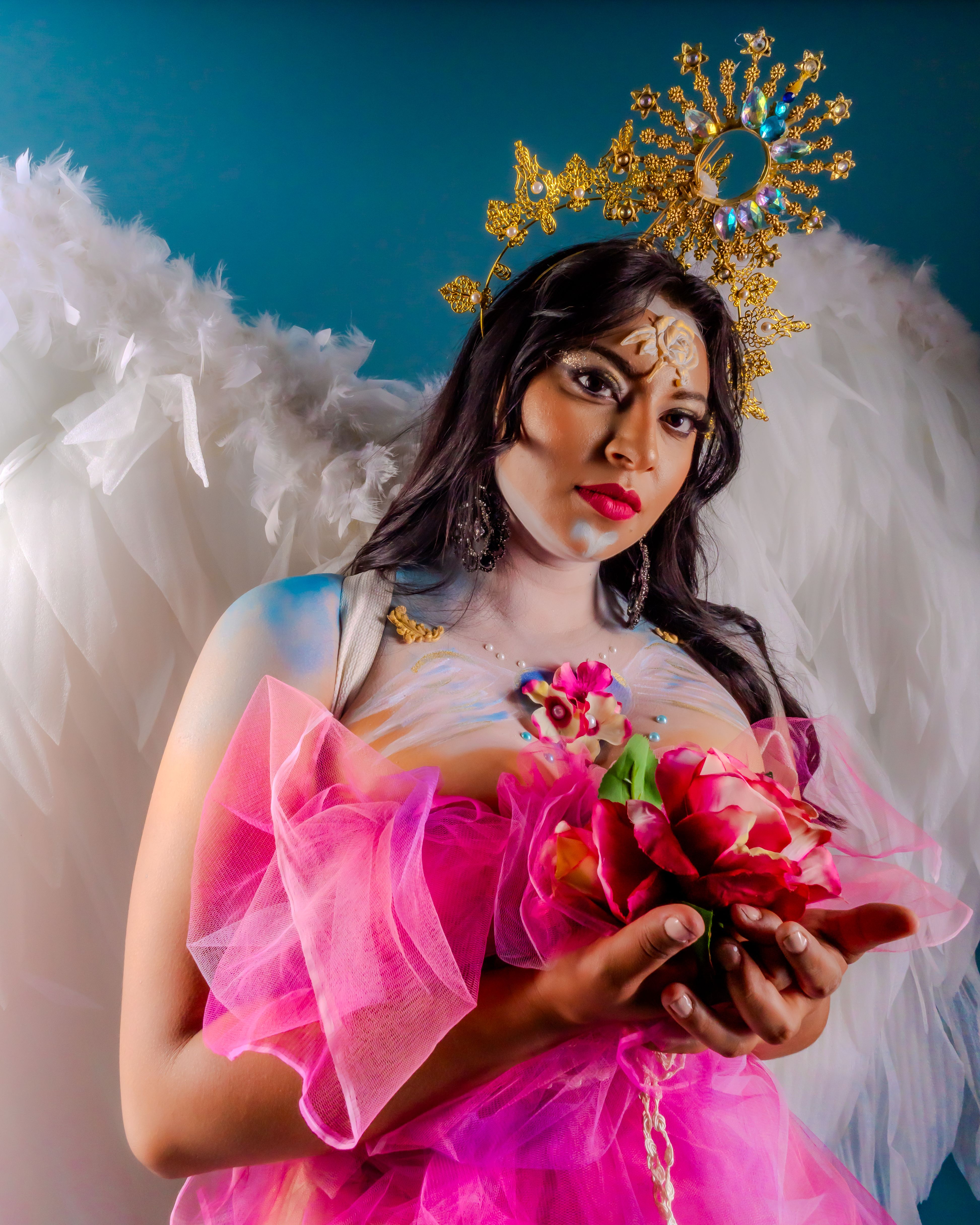 Stunning portrait of a woman with angelic wings holding flowers, showcasing vibrant colors and creative artistry.