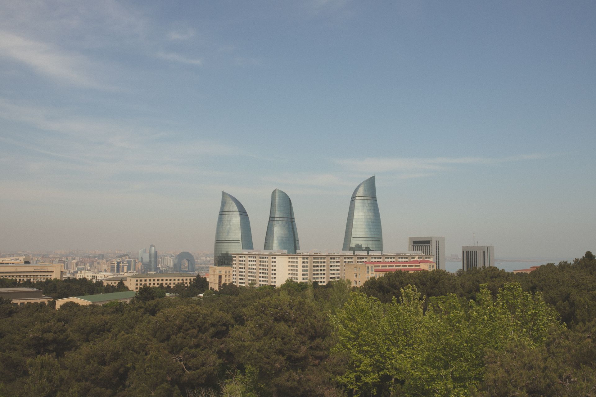 Scenic panorama of Baku's iconic Flame Towers with urban skyline and lush greenery.