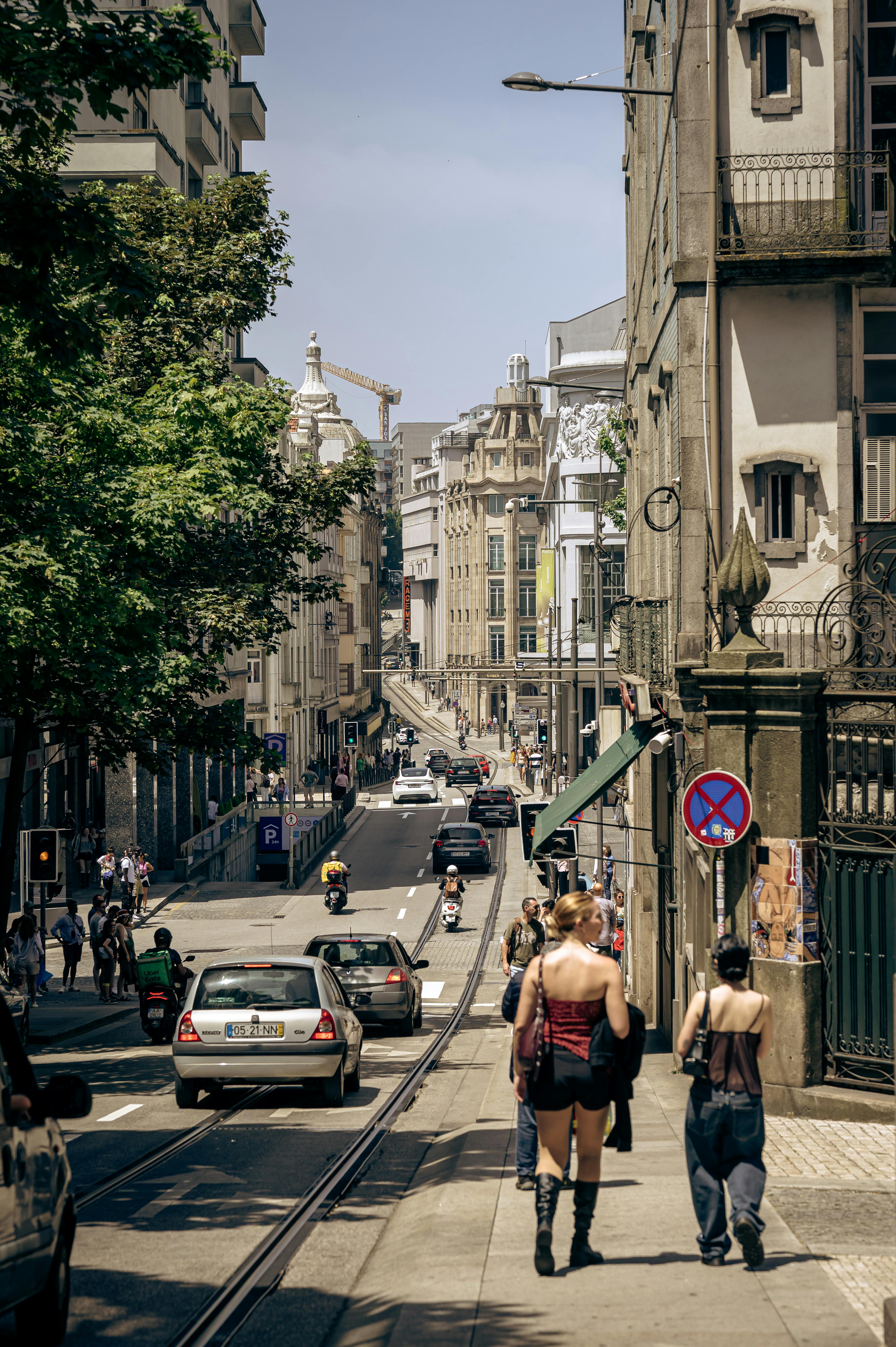 Busy urban street with pedestrians and traffic in a European city, showcasing vibrant summer day.