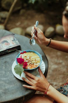 A vibrant breakfast bowl with fruits and flowers on a rustic table outdoors in Colombia.