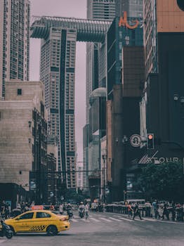 Dynamic Chongqing city street scene with skyscrapers and a crossing yellow taxi.