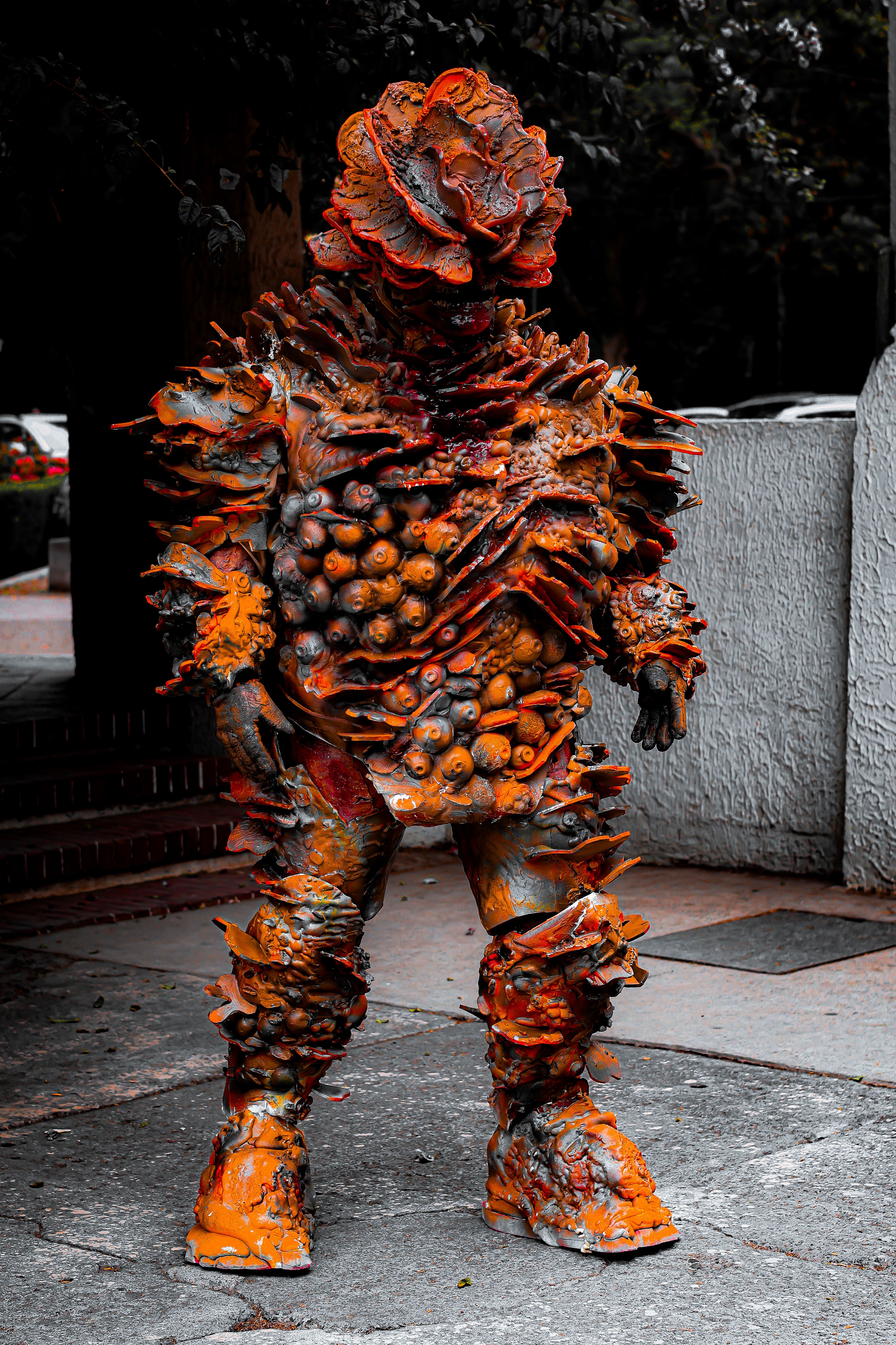 A person in an alien-inspired costume featuring spikes and organic textures, standing outdoors.