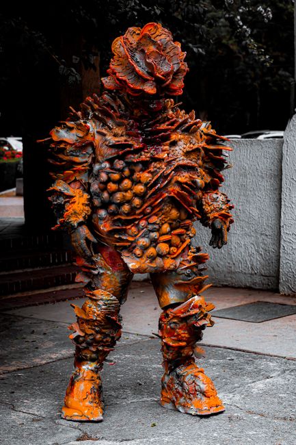 A person in an alien-inspired costume featuring spikes and organic textures, standing outdoors.