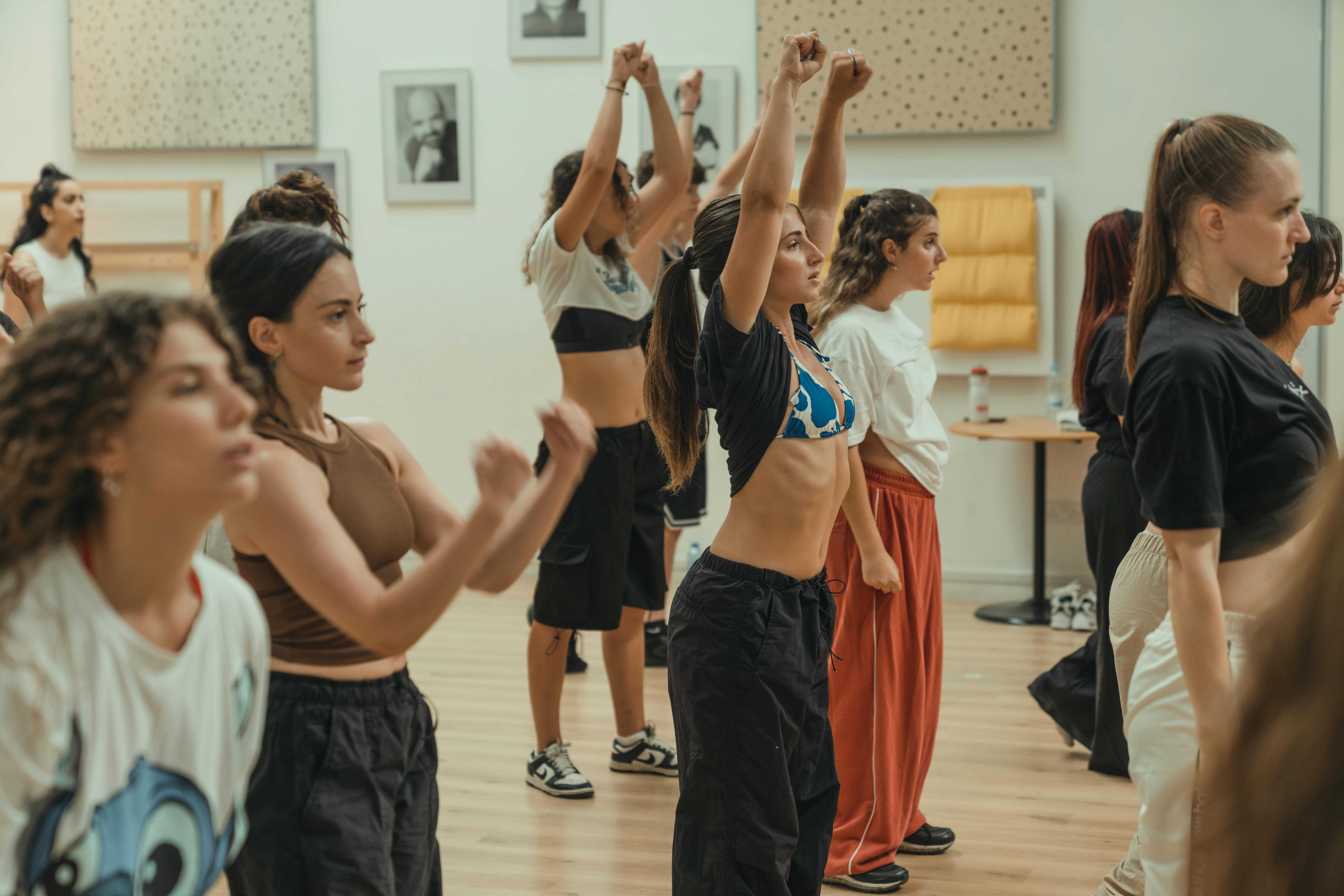 Energetic dance class with diverse group of young adults exercising together indoors.