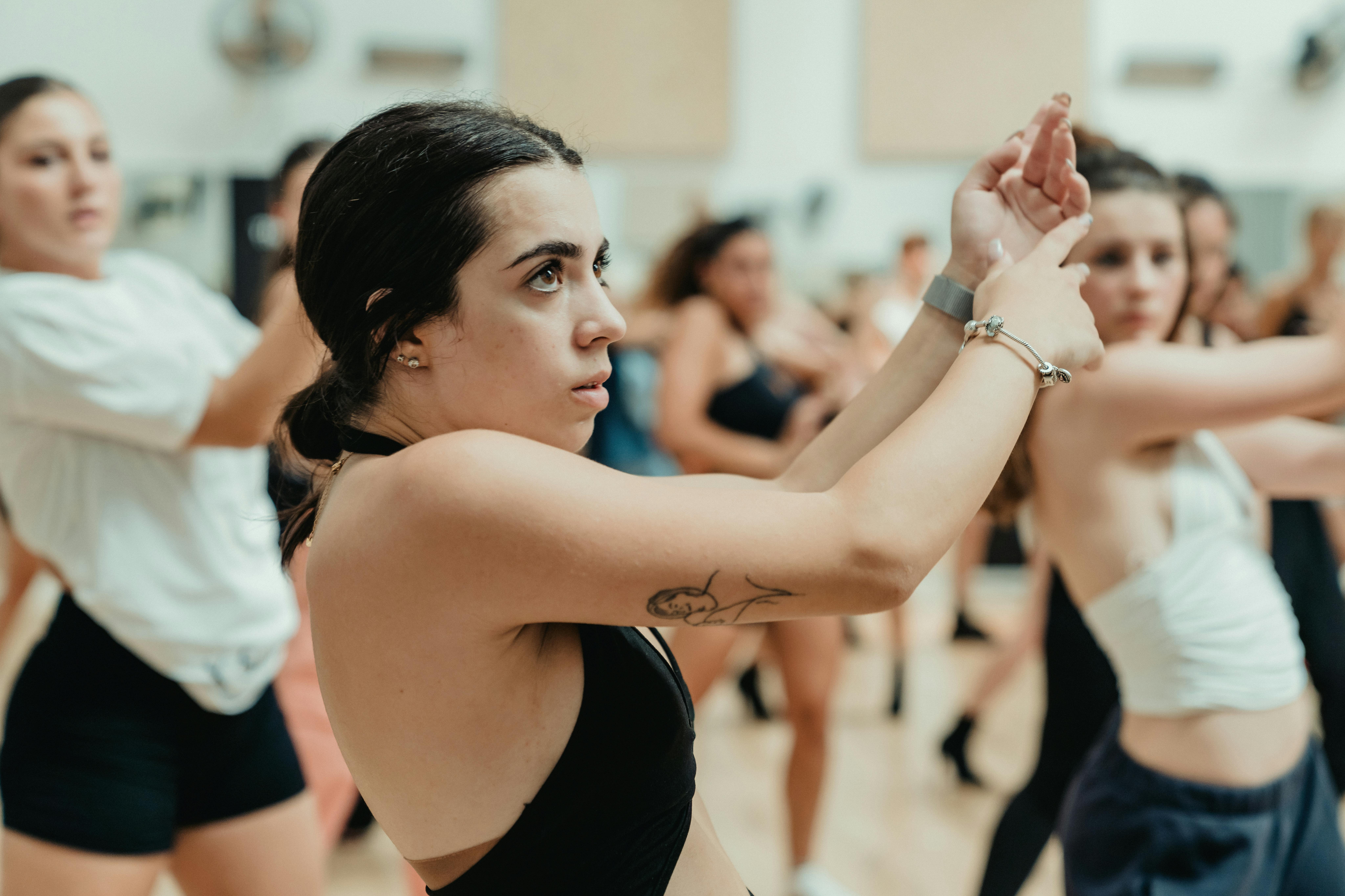 A group of focused young adults engaged in a dynamic dance class, highlighting movement and concentration.