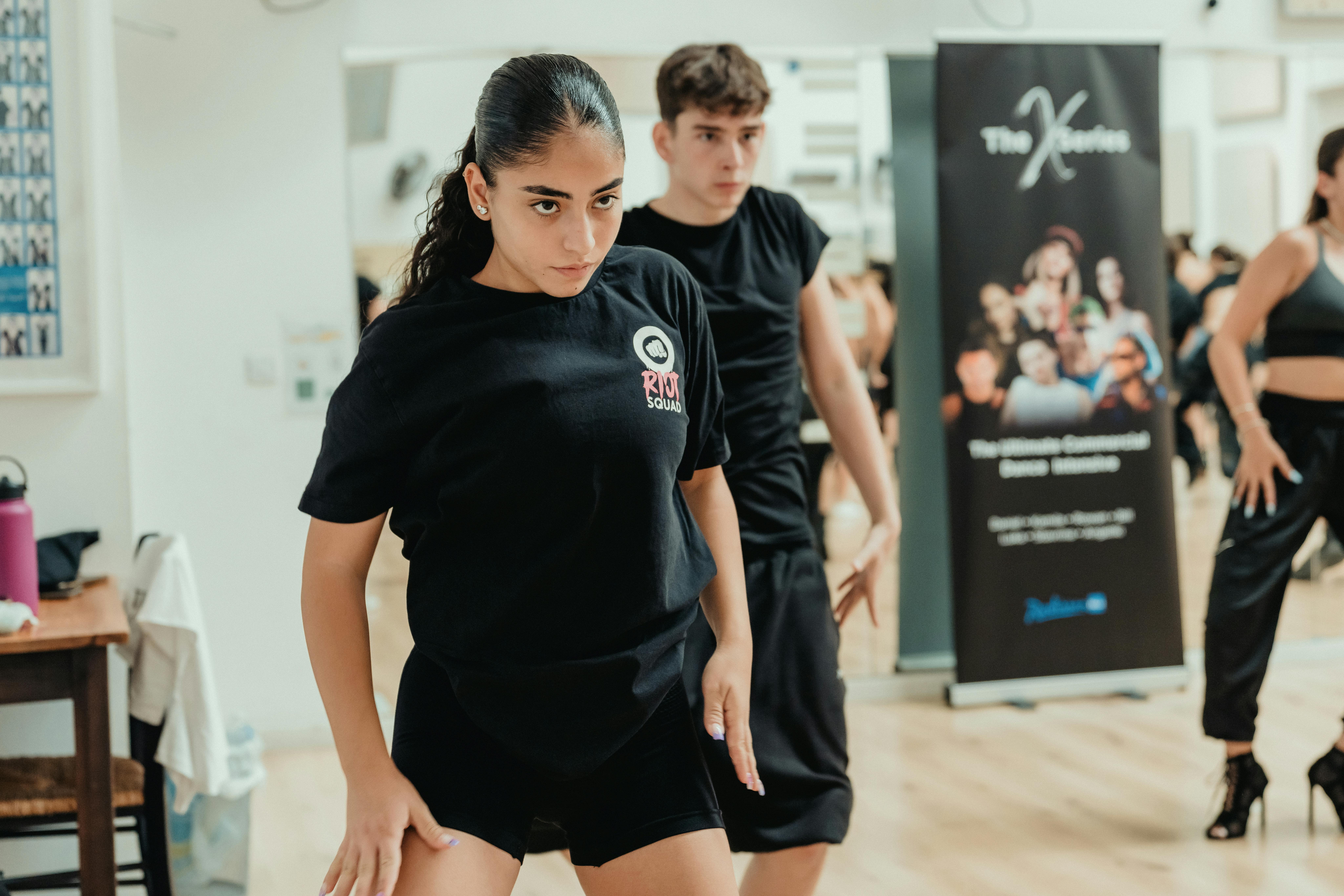 Energetic dance practice session with focused young adults in a studio.