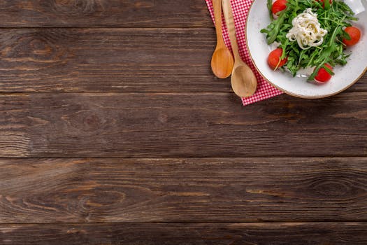 质朴的木桌上放着一盘美味的芝麻菜沙拉，配着樱桃番茄和意大利面，桌面上还留有空白的文字空间