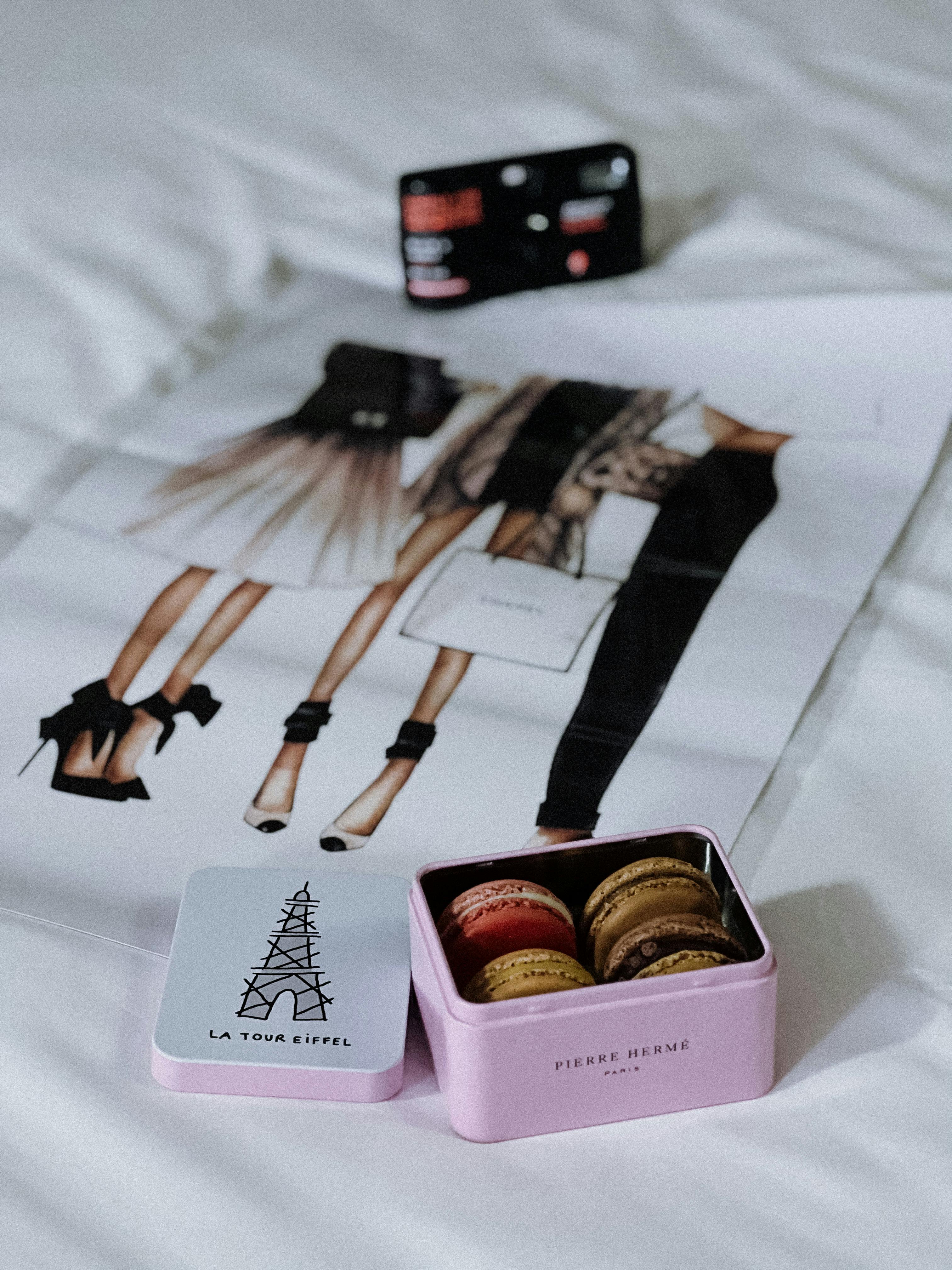 Free A chic display of colorful macarons by Pierre Hermé beside Paris fashion artwork and La Tour Eiffel card. Stock Photo