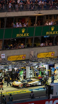 Dynamic scene of a busy night pit stop during the Le Mans race, showcasing teamwork and precision.