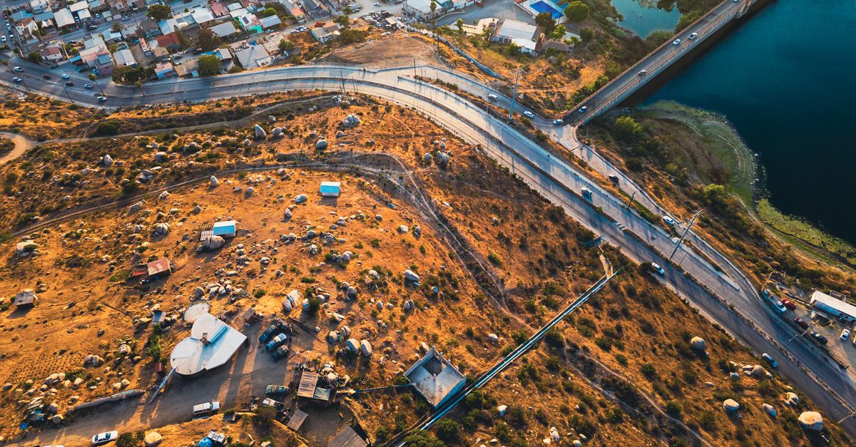 Aerial shot capturing urban and rural contrast with roads and lake.