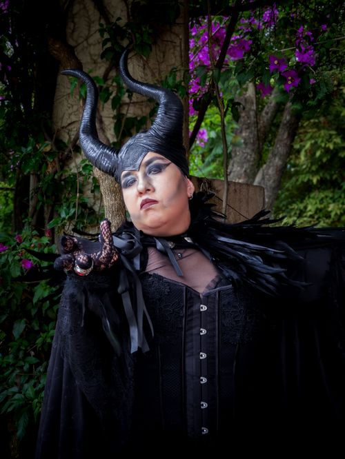 Free A captivating figure in dark costume and makeup posing dramatically amidst lush, vibrant foliage. Stock Photo