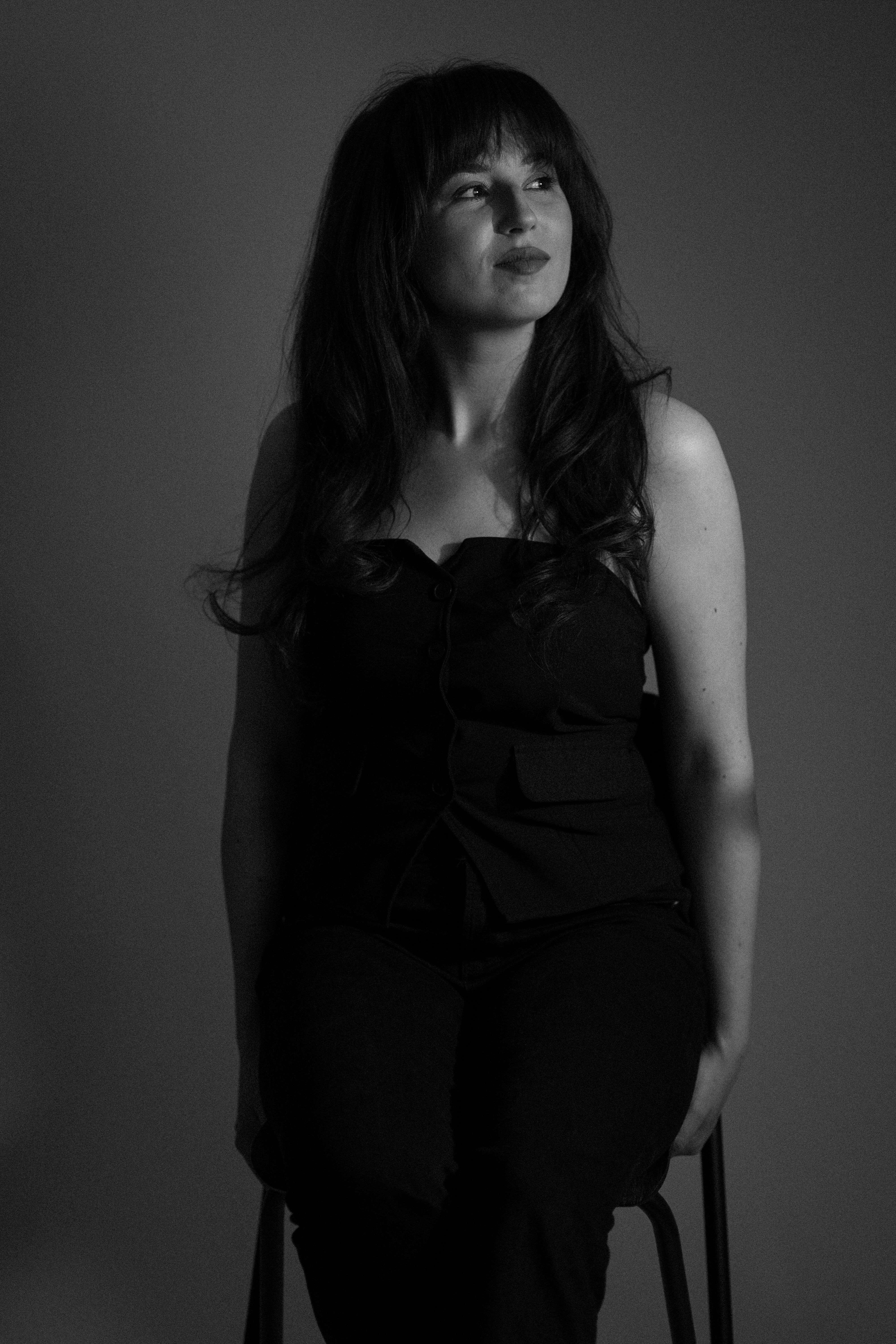 A captivating black and white studio portrait of a woman seated with a thoughtful gaze.