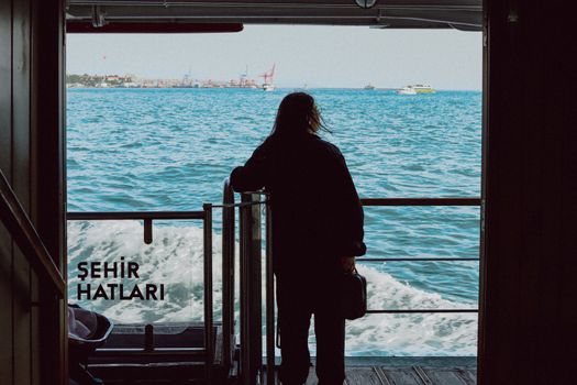 Silhouette of person on ferry with ocean view, capturing serene travel vibe in daylight.