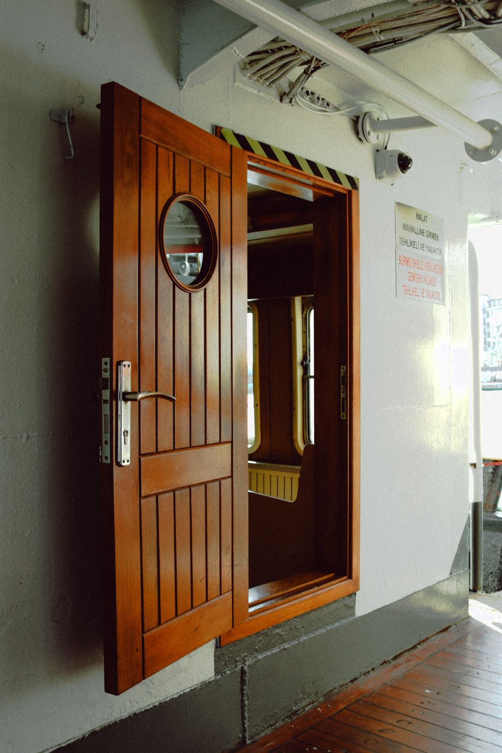 Varnished yacht cabin door with a round porthole, closed against daylight