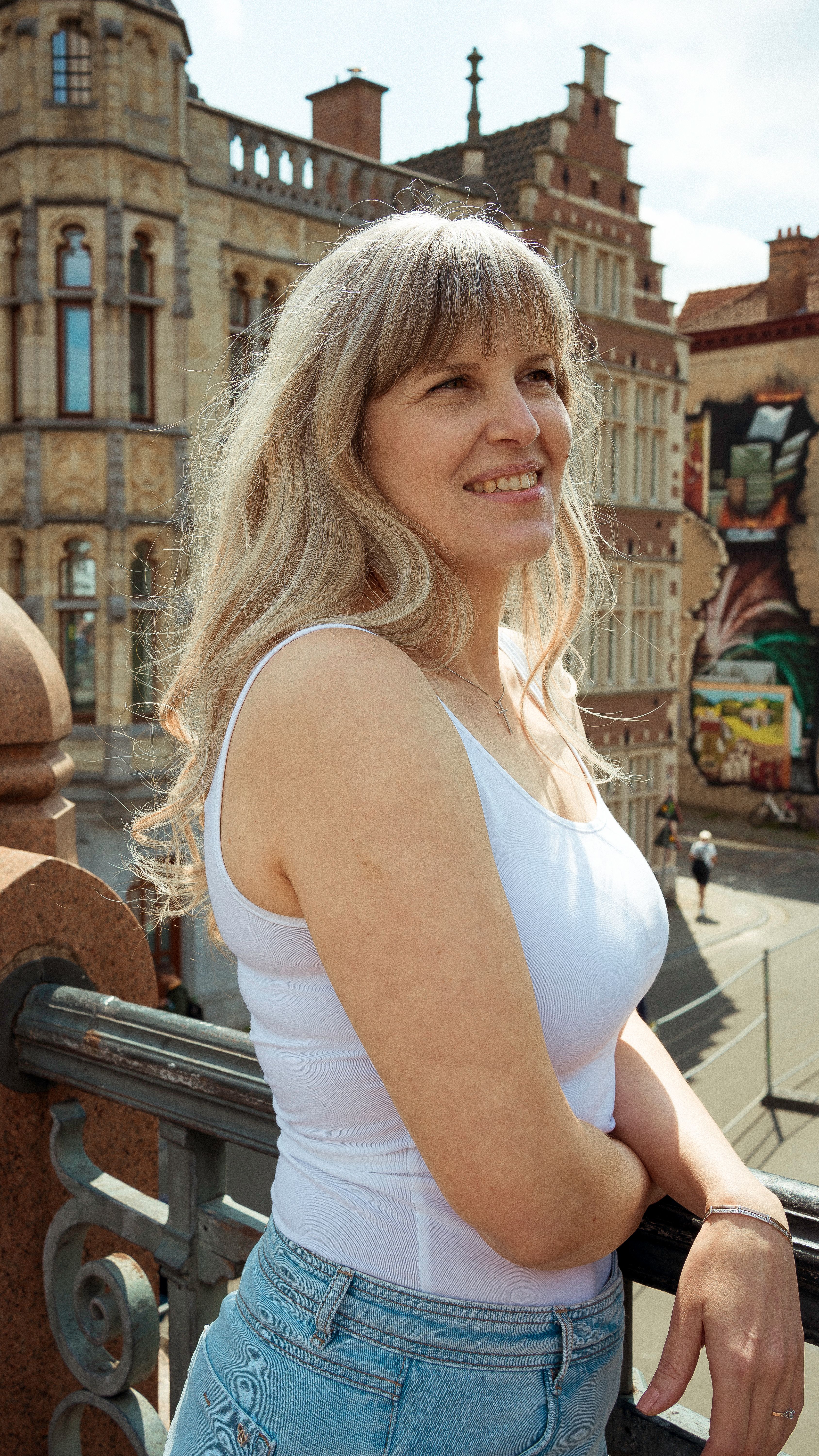 Blonde woman admiring the view from a historic bridge in Ghent, Belgium.