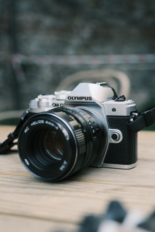 Free Close-up of a classic Olympus OM-D camera with a Helios lens displayed on a wooden surface. Stock Photo