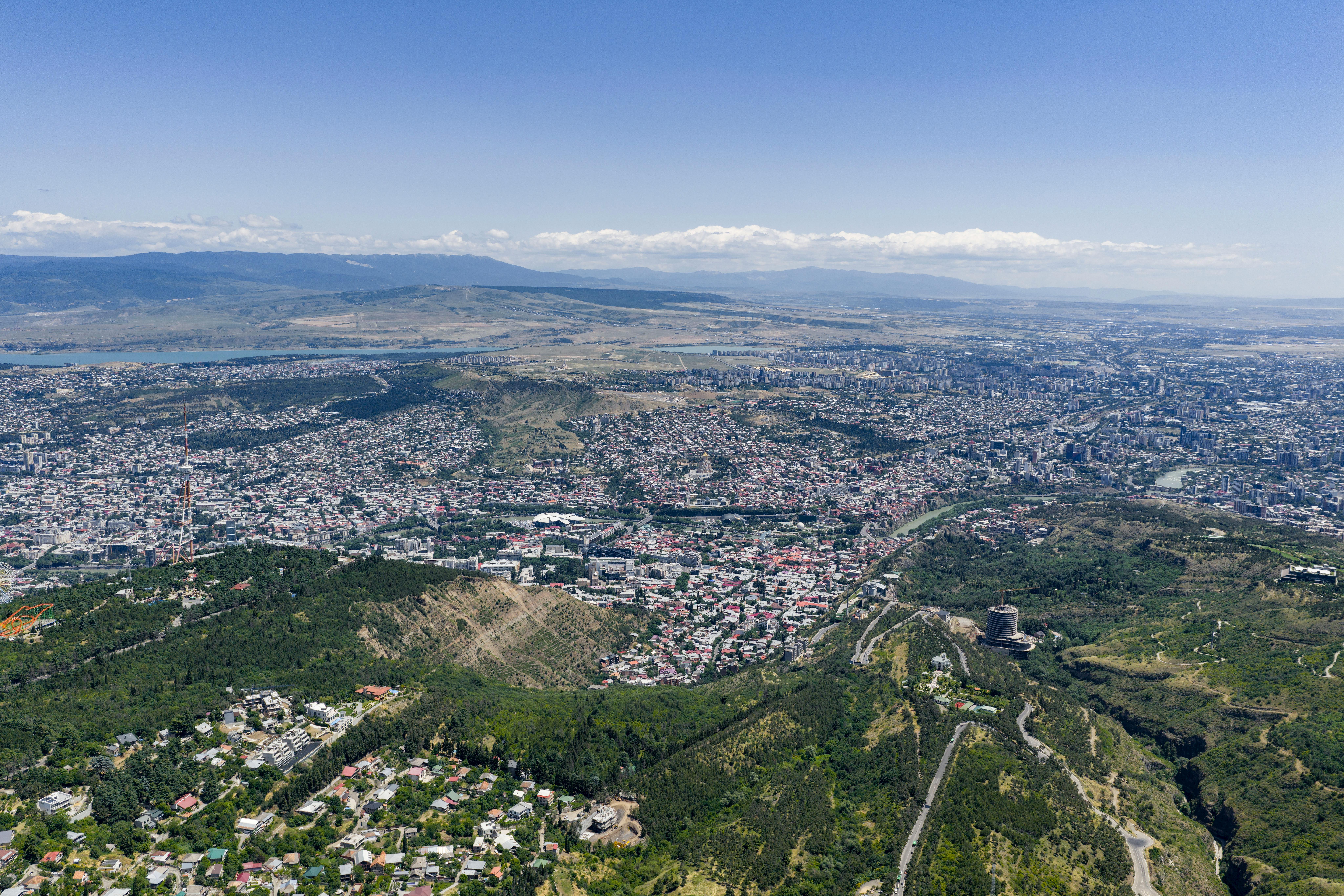Fotografía aérea impresionante que muestra el extenso paisaje urbano de Tbilisi, Georgia, contra un cielo azul claro.