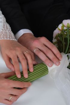 A close-up shot of a couple's hands holding a wedding bouquet with pink flowers.