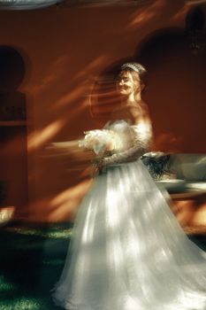 Beautiful bride in flowing gown with motion blur, bathed in warm sunlight for a dreamy effect.