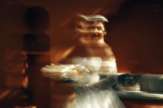 Artistic shot of a bride with a motion blur effect creating an ethereal appearance indoors.