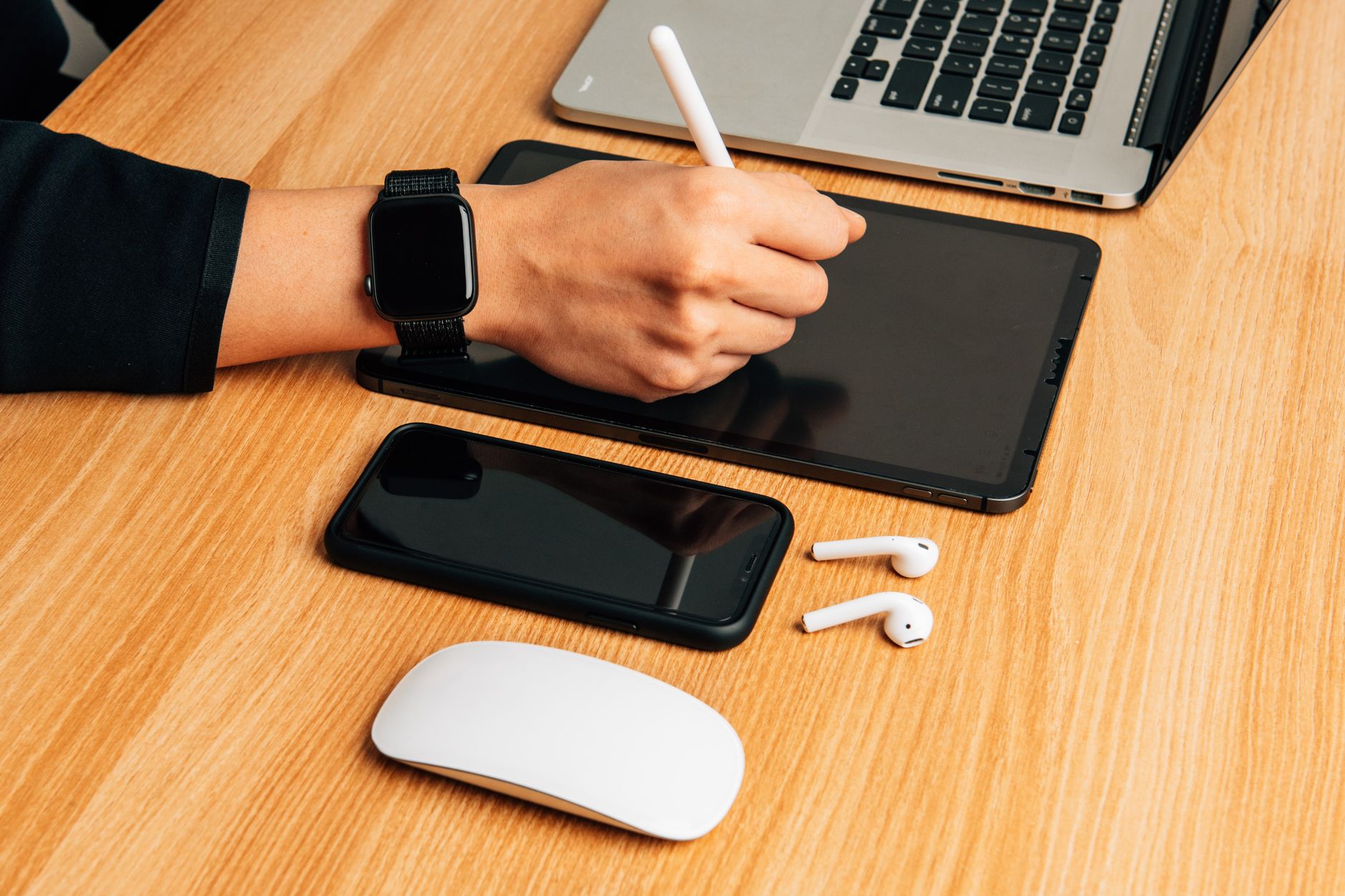 Top view of a modern office desk with gadgets including iPad, smartphone, and AirPods.