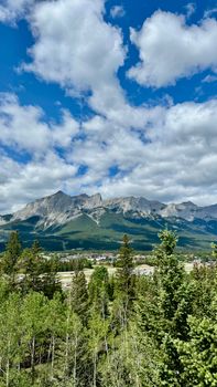 Breathtaking view of the Rocky Mountains under a bright blue sky with clouds.