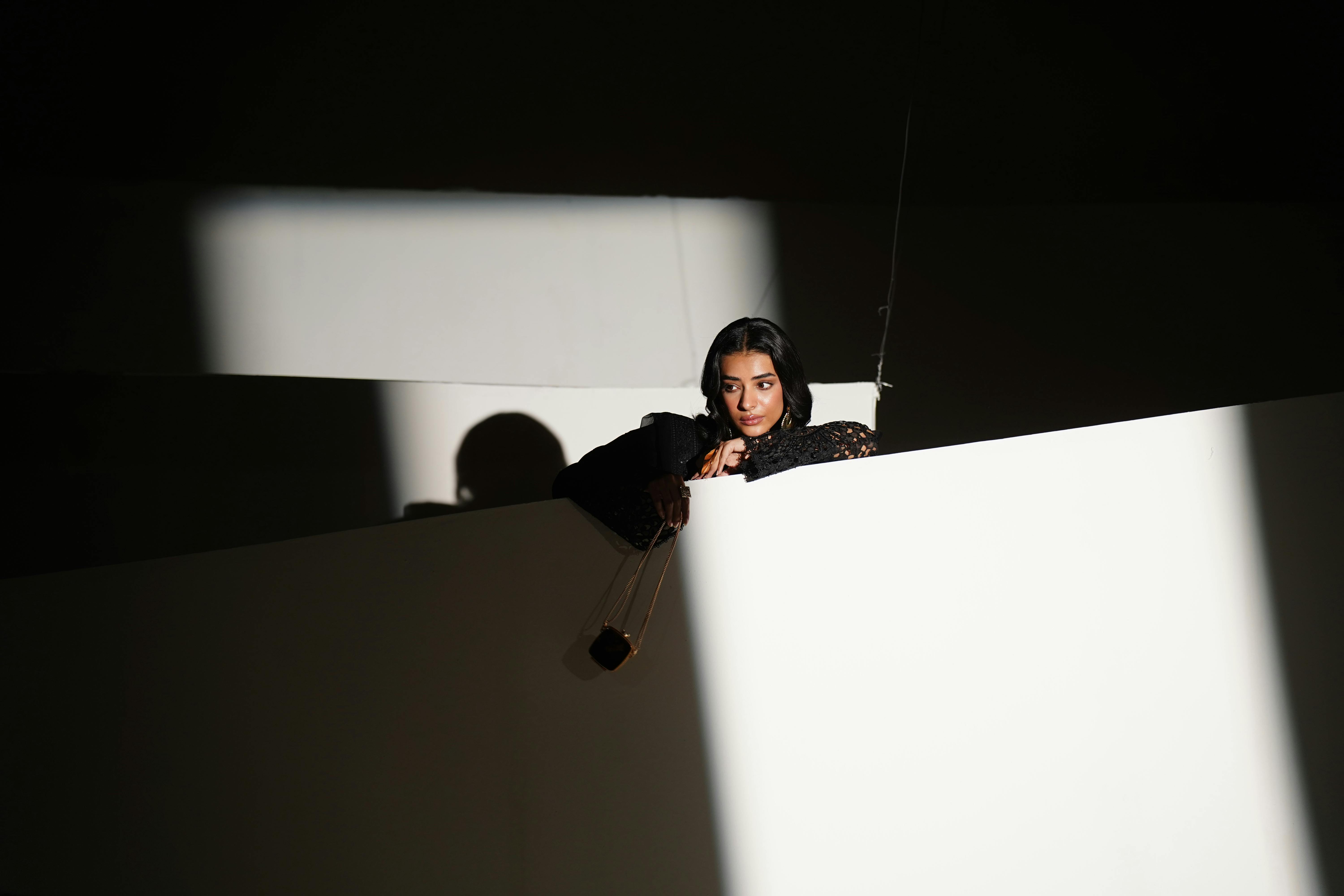 Gratis Mujer elegante con vestido negro posando con sombras que crean un efecto visual dramático. Capturada en Lahore, Pakistán. Foto de stock