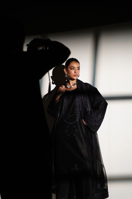 Fashion model in embroidered black dress posing with dramatic lighting in Lahore.