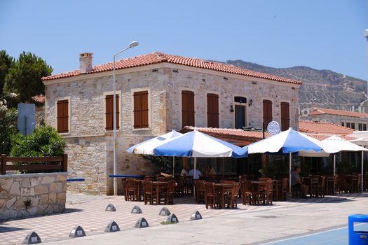 Beautiful stone cafe with umbrellas and wooden furniture in Foça, İzmir, Türkiye.