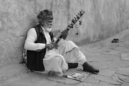 An elderly Indian man plays a sarangi on a street in Jaipur, Rajasthan, capturing cultural essence.