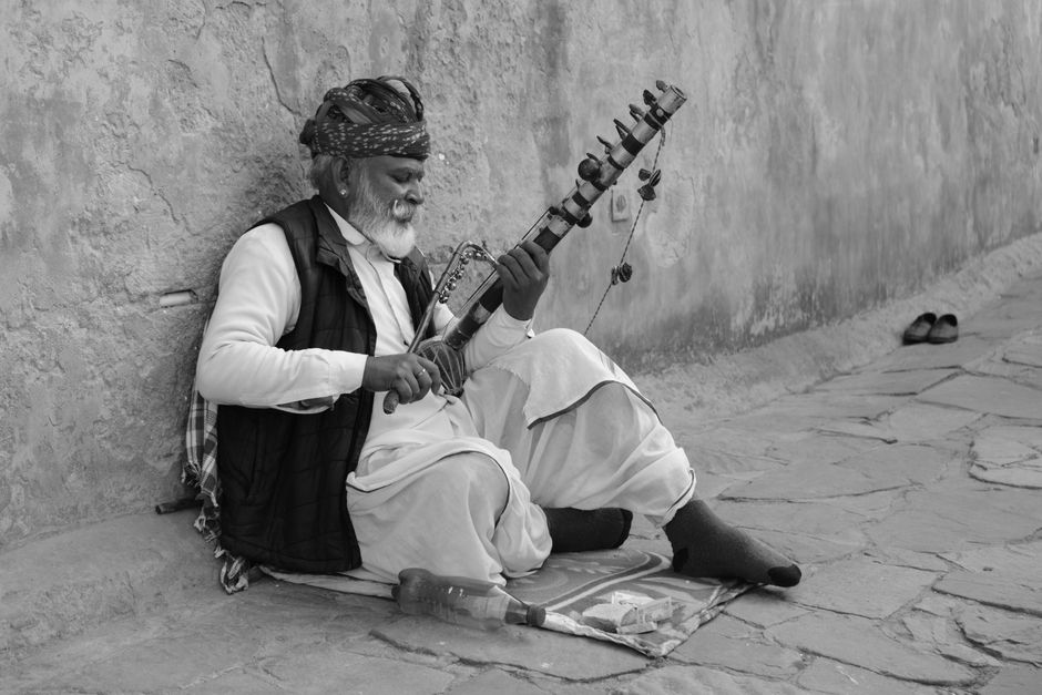 An elderly Indian man plays a sarangi on a street in Jaipur, Rajasthan, capturing cultural essence.