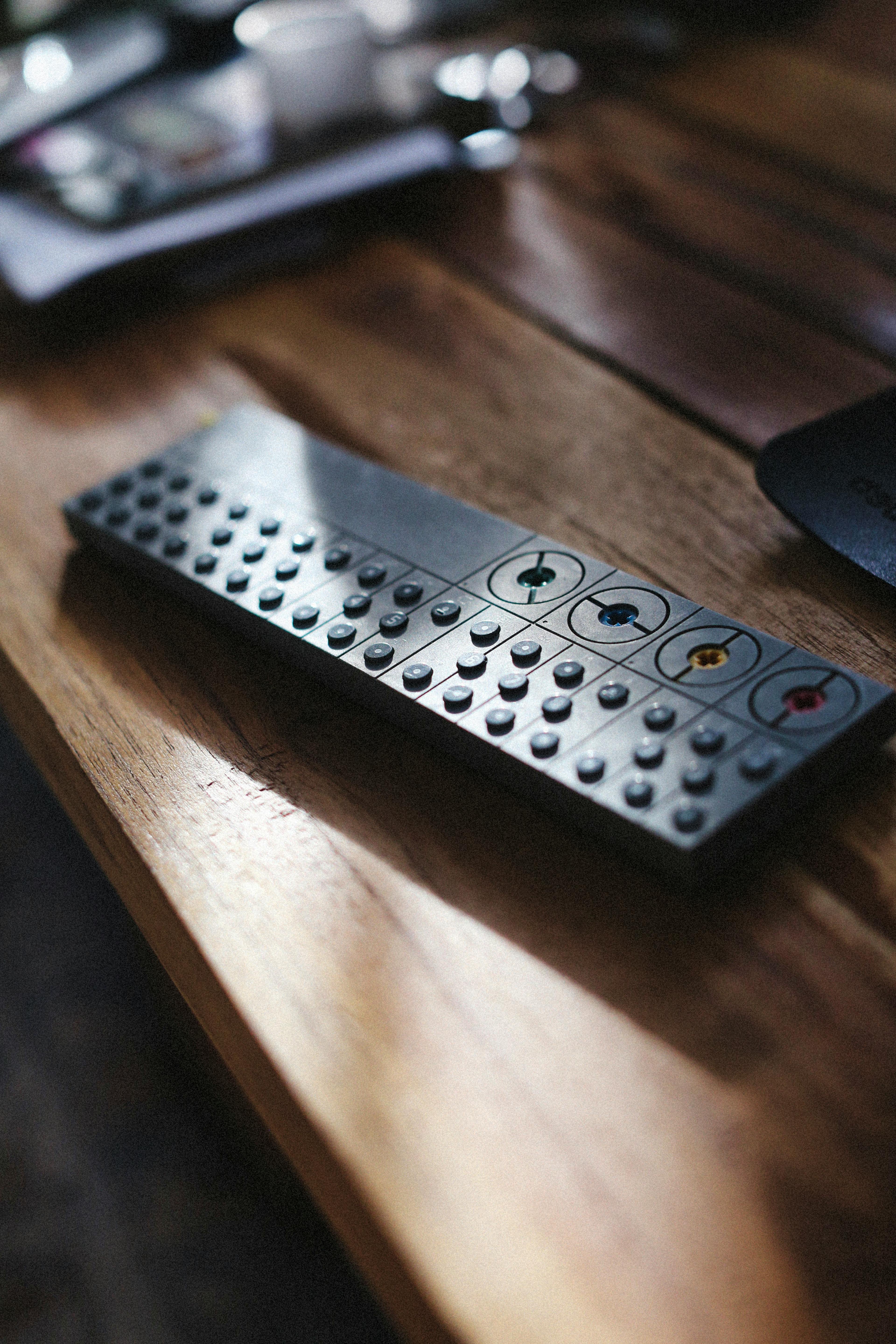 Artistic shot of a music controller with buttons on a wooden surface, casting shadows.