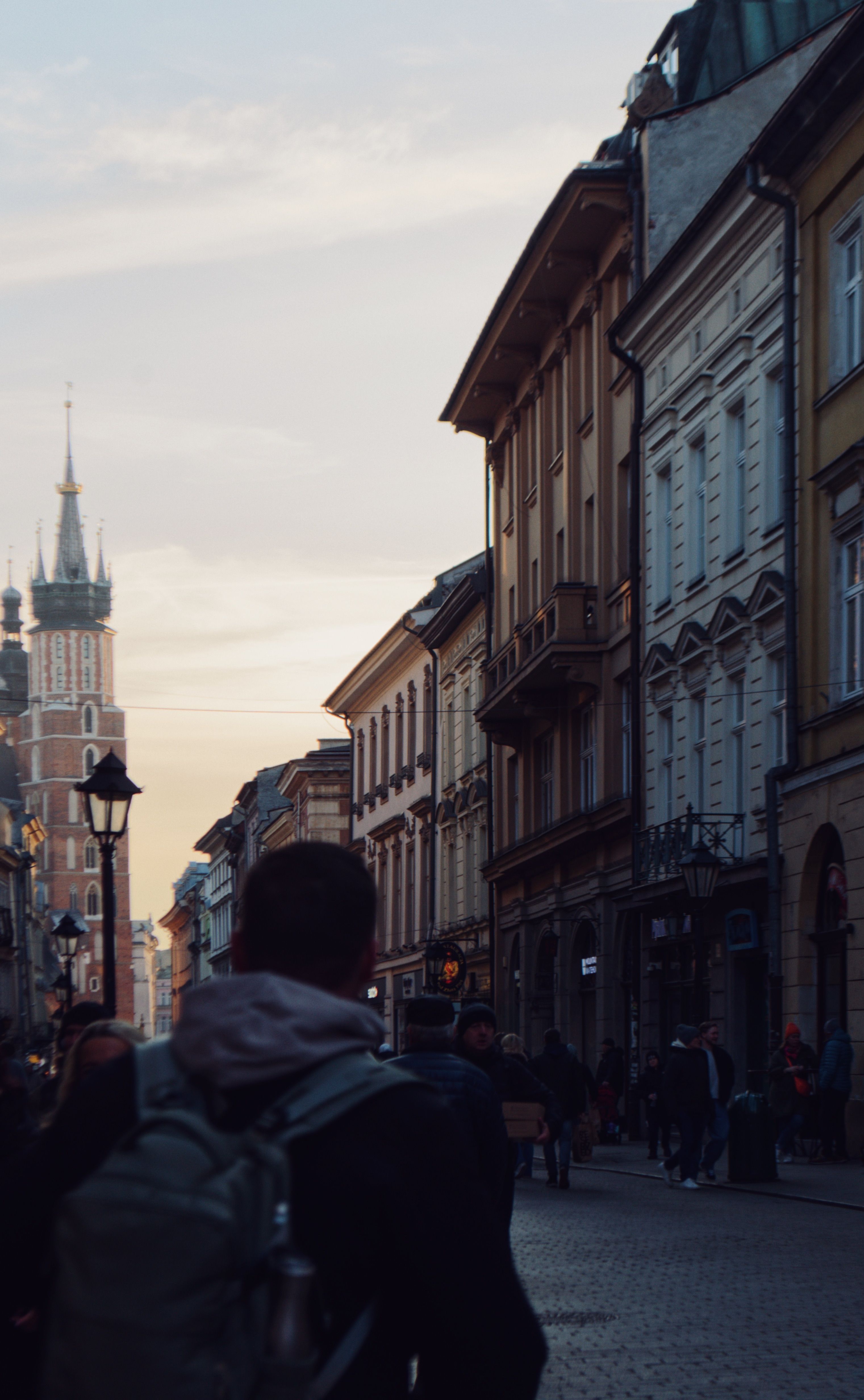Charming view of Kraków streets at sunset with St. Mary's Basilica in the background, capturing the city's essence.