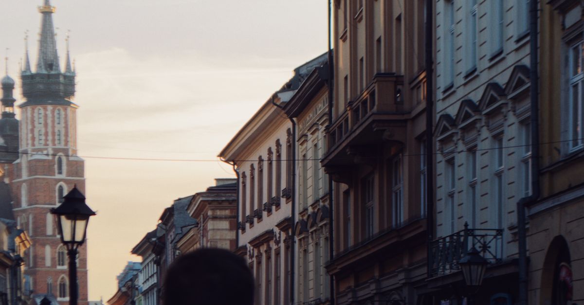Charming view of Kraków streets at sunset with St. Mary's Basilica in the background, capturing the city's essence.