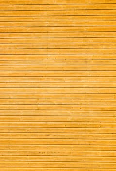 Close-up of yellow wooden plank wall with horizontal lines creating a classic texture.