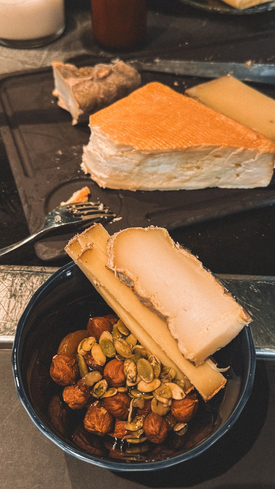 A washed-rind cheese dominating a dark rustic board