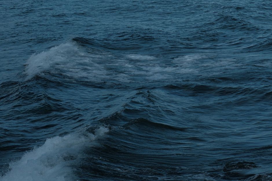 Fotomural Olas del océano azul oscuro que crean un paisaje marino sereno y melancólico en un día nublado.