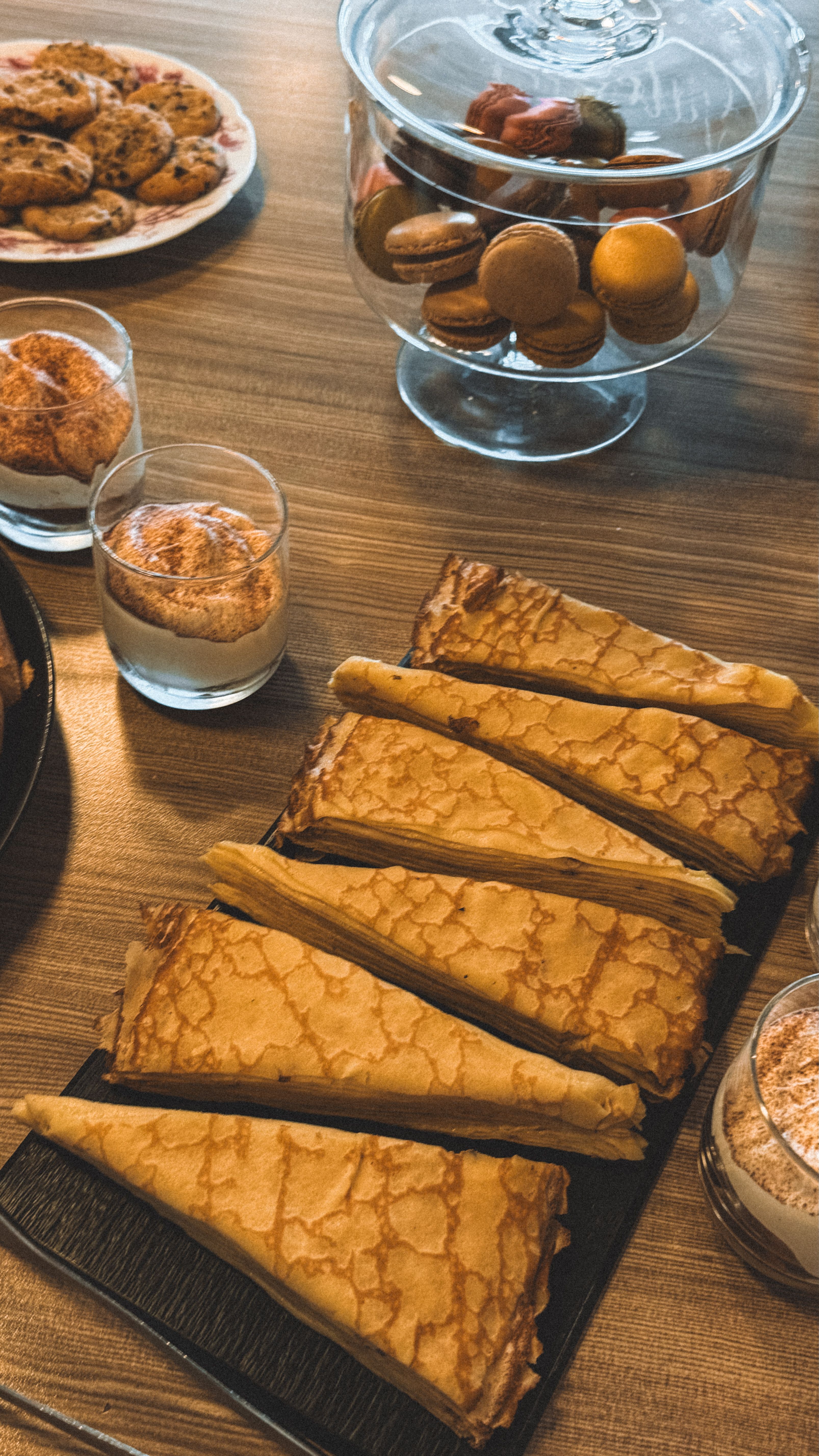Tasty variety of crepes and pastries on a wooden table, perfect for breakfast.