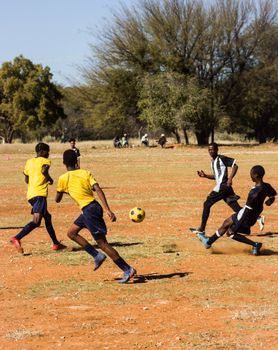 Boys playing soccer on a sunny day in an open field, engaging in competitive sports.