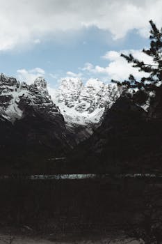 Breathtaking view of the snow-capped Dolomites mountains under a cloudy sky, ideal for travel inspiration.
