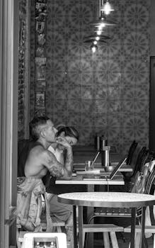 A couple enjoying a quiet moment in a cozy Madrid cafe, captured in black and white.