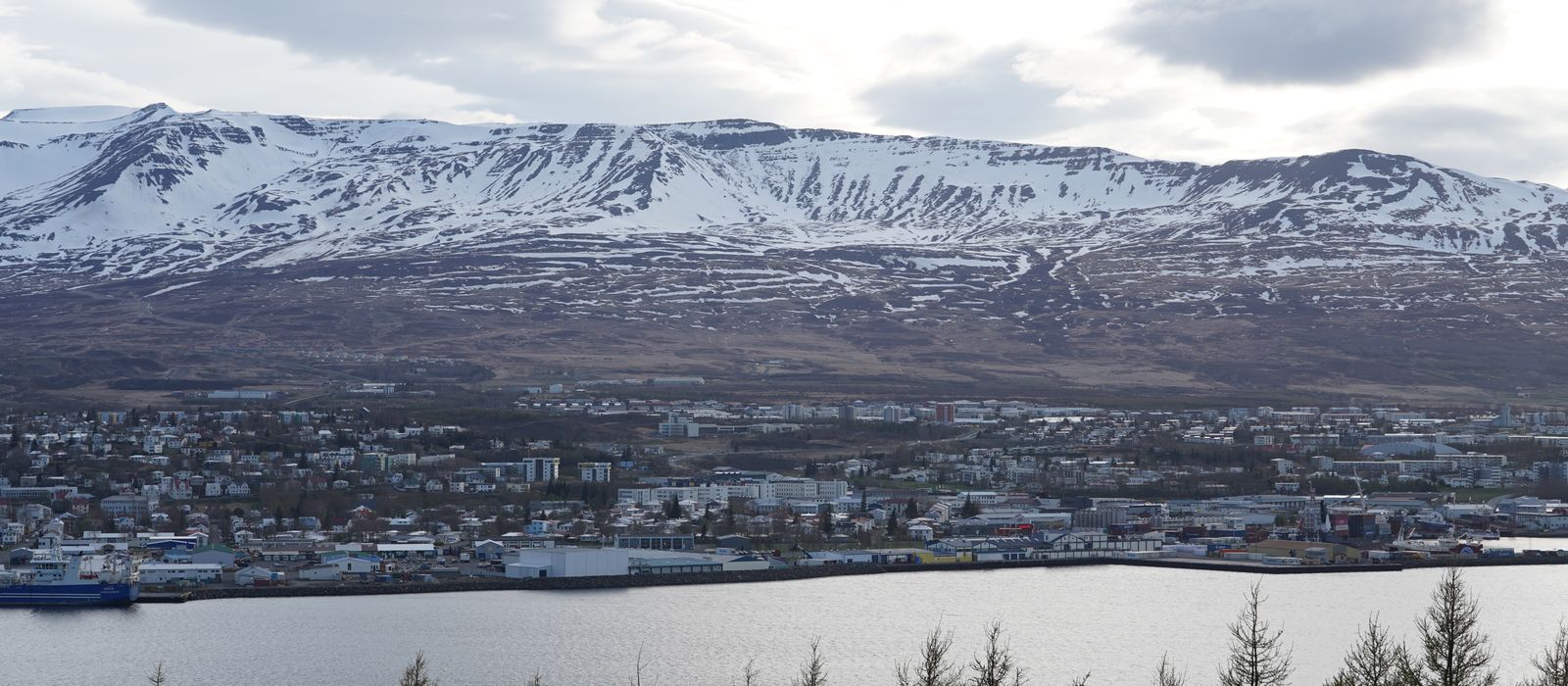 Serene aerial view of Akureyri, Iceland featuring snowcapped mountains and a peaceful harbor.