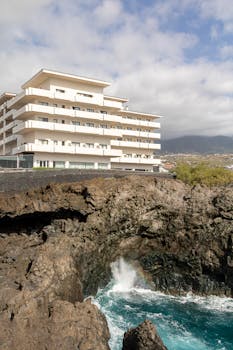 Modern apartment building next to rocky coast in La Palma, Spain.