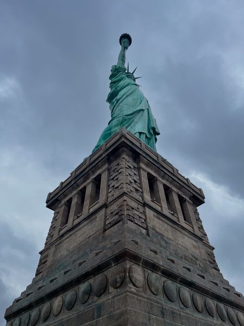 Free Low angle view of the Statue of Liberty under a dramatic cloudy sky in New York City. Stock Photo