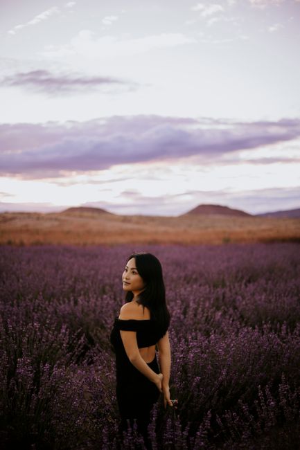 Woman standing in a vast lavender field during twilight, creating a tranquil scene.