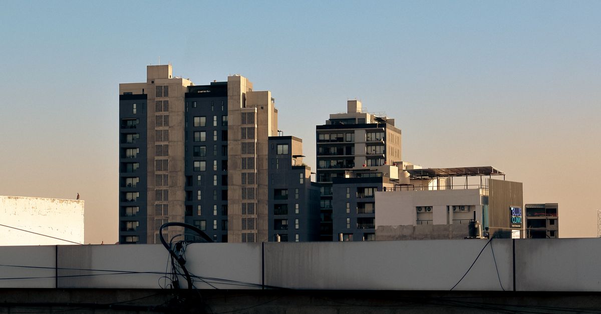 A cityscape featuring modern high-rise buildings silhouetted against a clear evening sky.