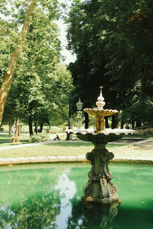 Free Tranquil vintage fountain in a beautiful greenery-filled park, perfect for nature lovers. Stock Photo