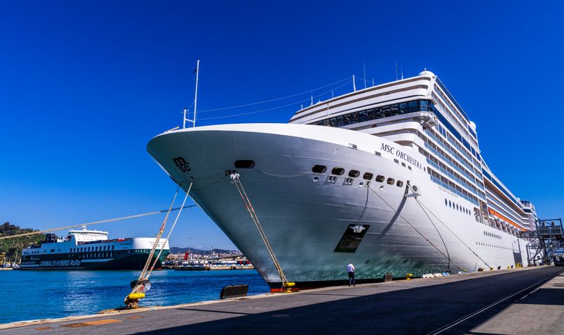 A large cruise ship docked at Barcelona port under a clear blue sky, showcasing maritime travel.
