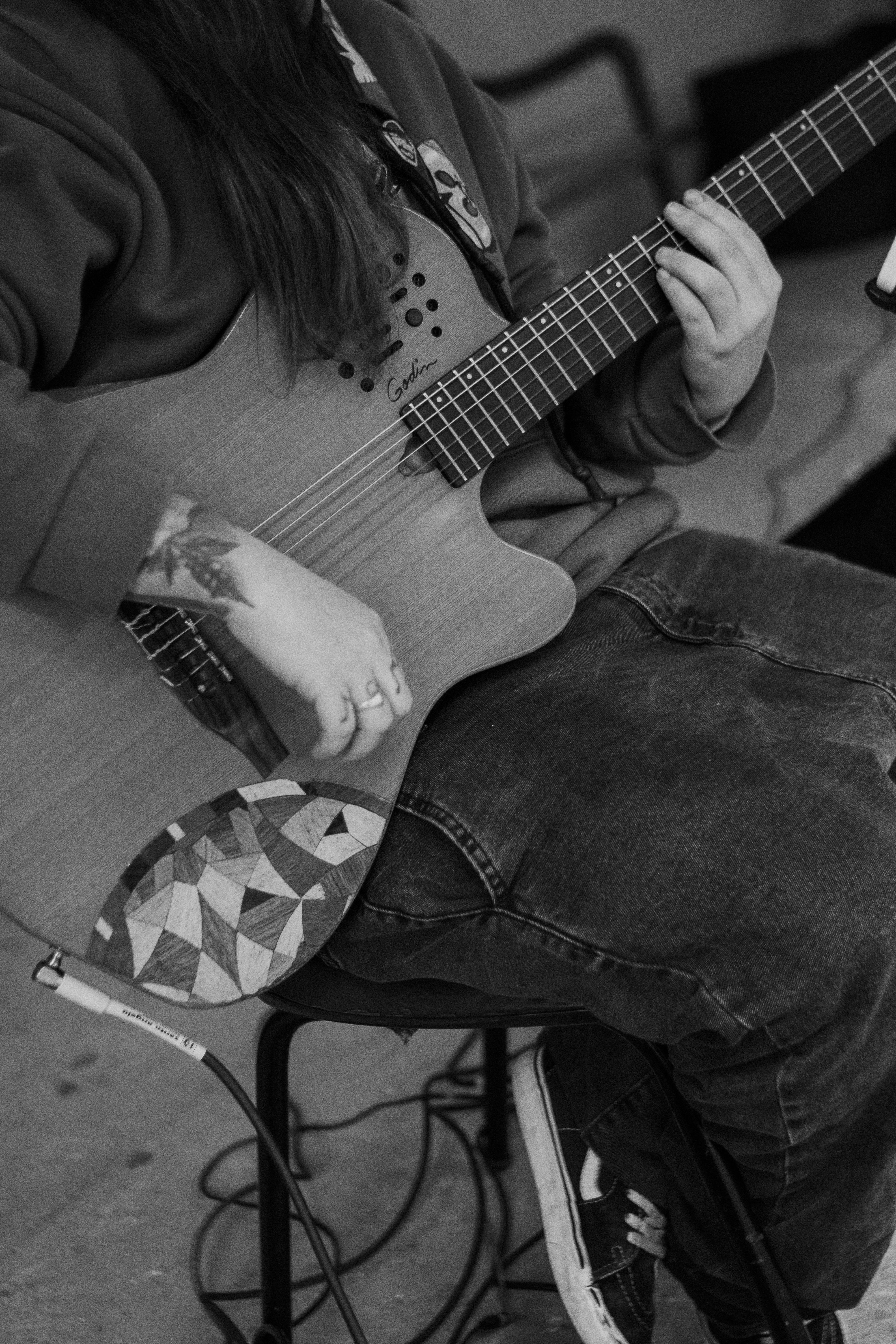 Monochrome image of a person playing an acoustic guitar, focusing on hands and tattoo details.. pexels, monochrome, image